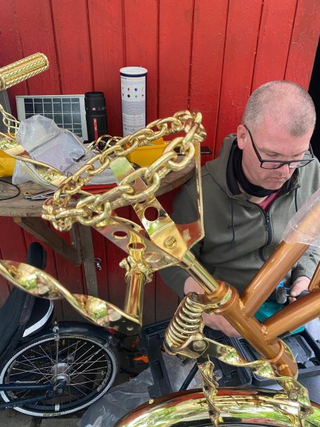 Mann arbeitet an einem kunstvoll verzierten Fahrradrahmen aus Gold.