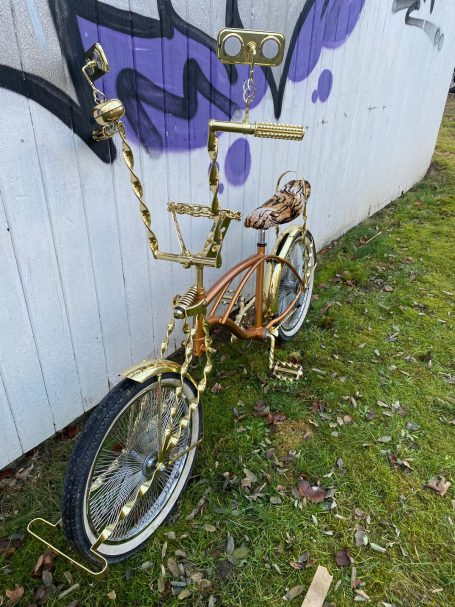 Kunstvolle, goldene Fahrradszene mit ungewöhnlichem Design und Graffiti-Hintergrund.